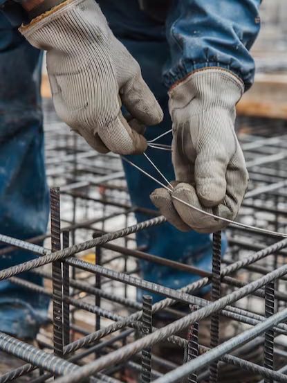 Worker tying steel reinforcement bars on site